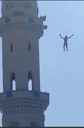 Homme sautant d'une tour célèbre avec un ciel bleu en arrière-plan.
