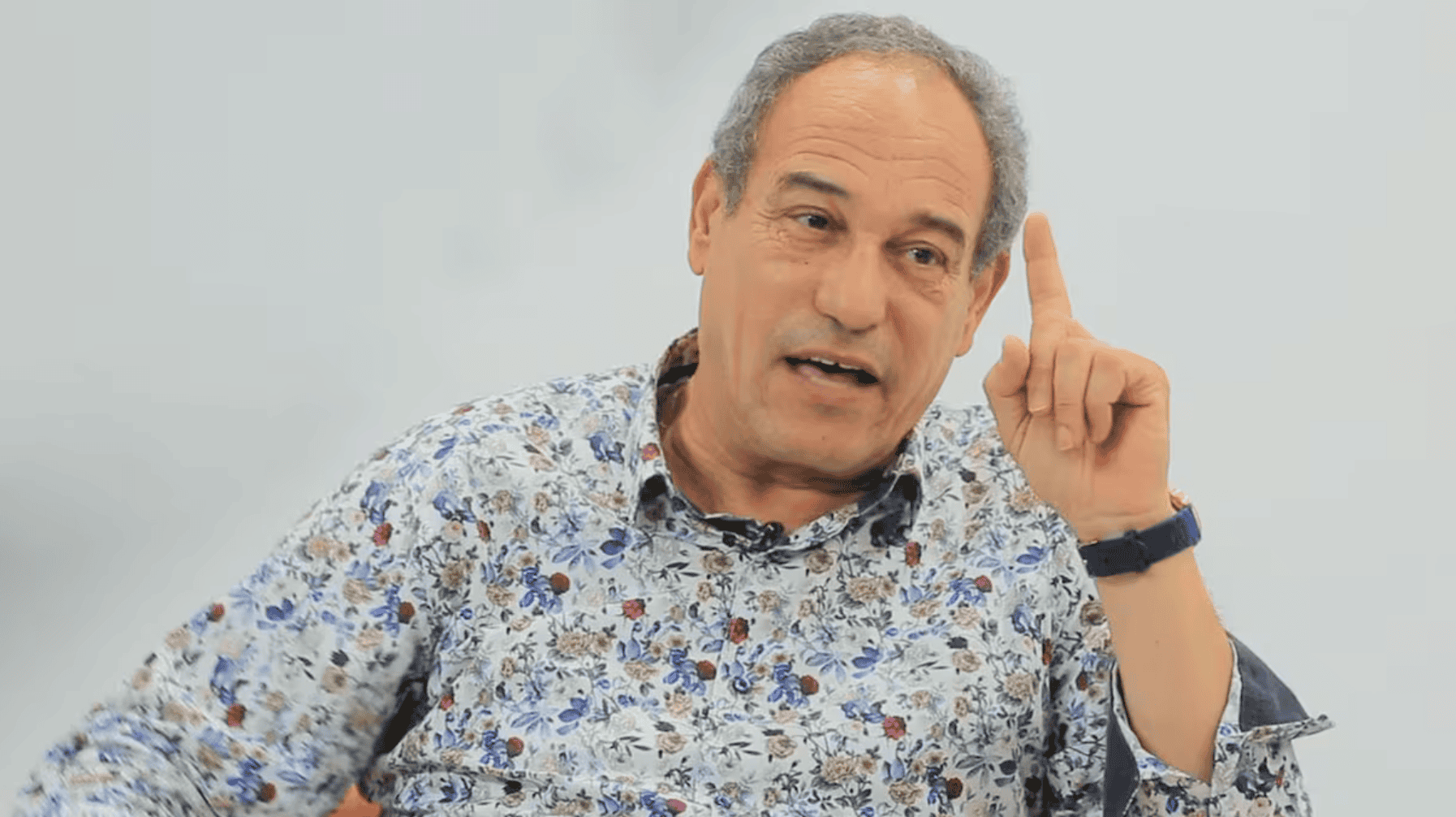 Hichem Aboud parlant, geste de la main, expression sérieuse.