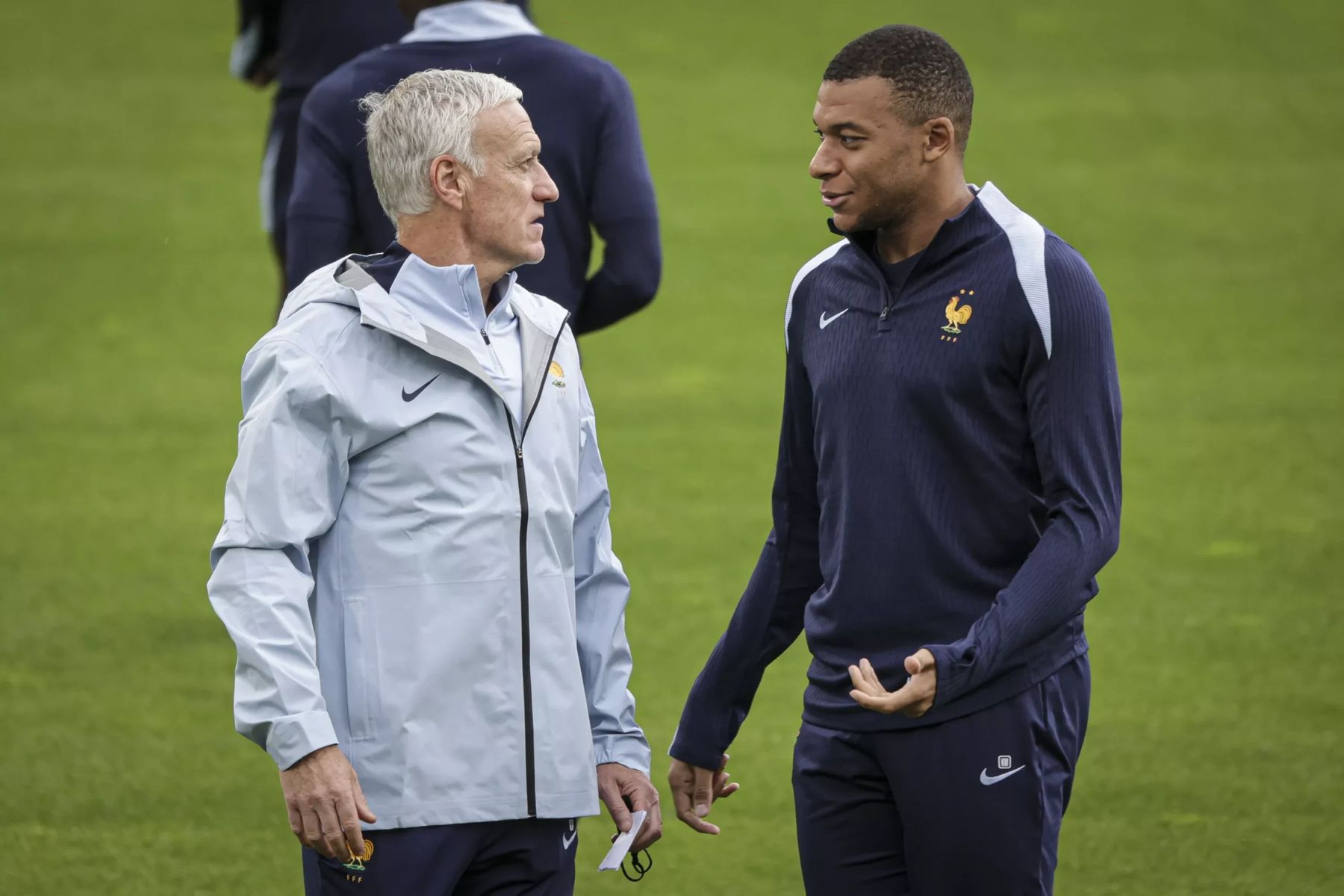 Didier Deschamps et Kylian Mbappé en discussion sur le terrain.