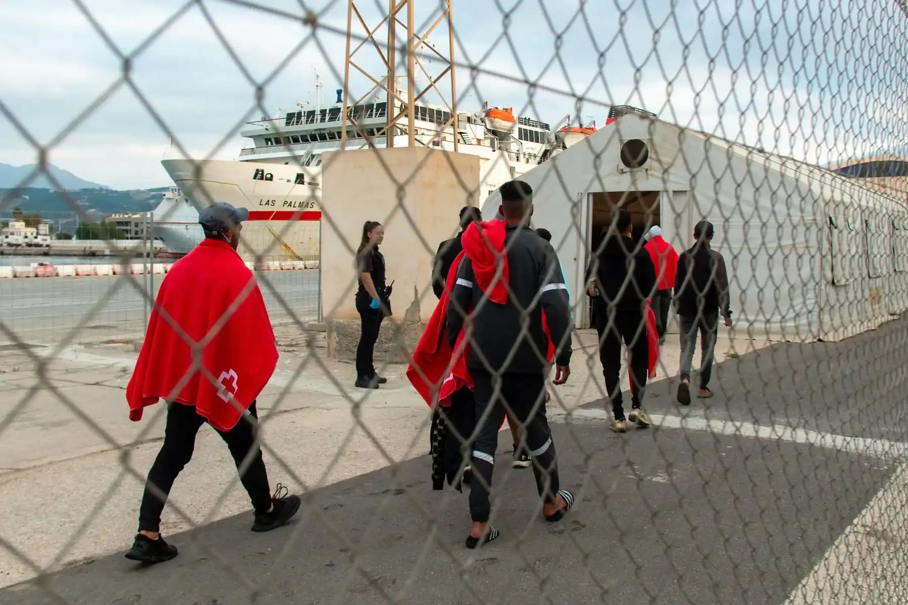 Migrants traversant le port en direction d'un bateau de pêche.