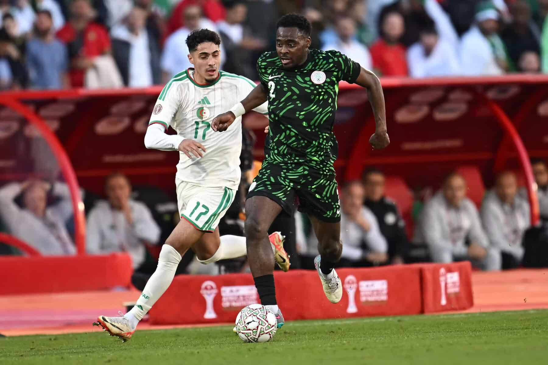 Joueur nigérian et algérien en duel lors d'un match de football.
