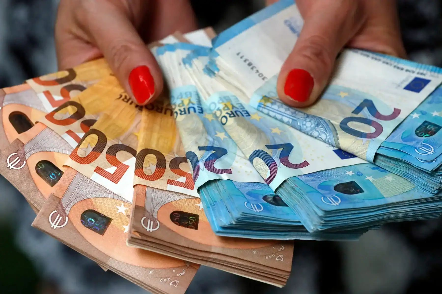 Main tenant un tas de billets d'euros de différentes coupures.