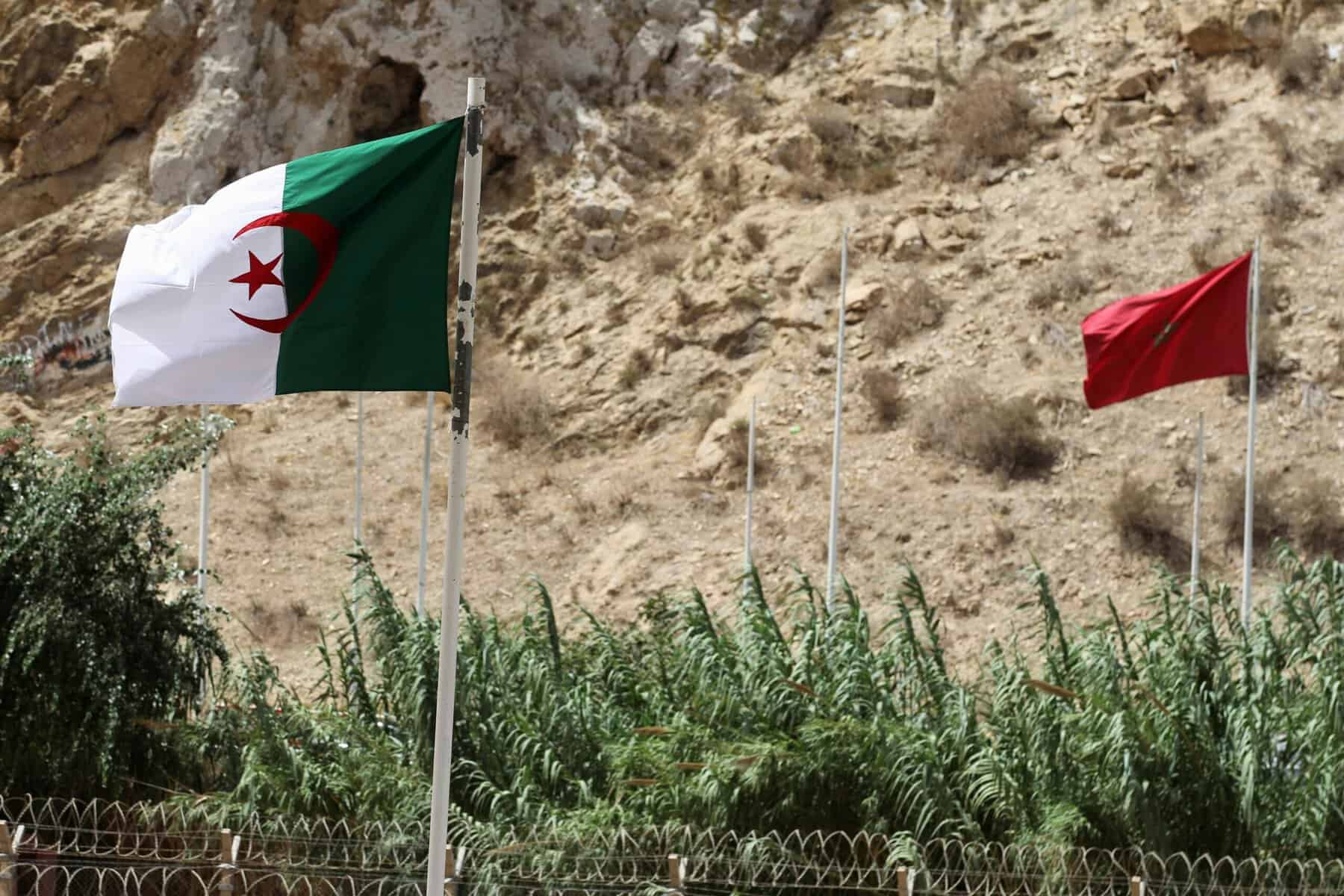 Drapeaux d'Algérie et du Maroc dans un paysage désertique.