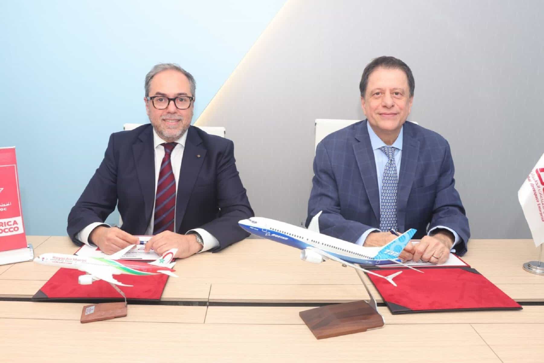 Deux hommes signent un accord avec des modèles d'avions en miniature.