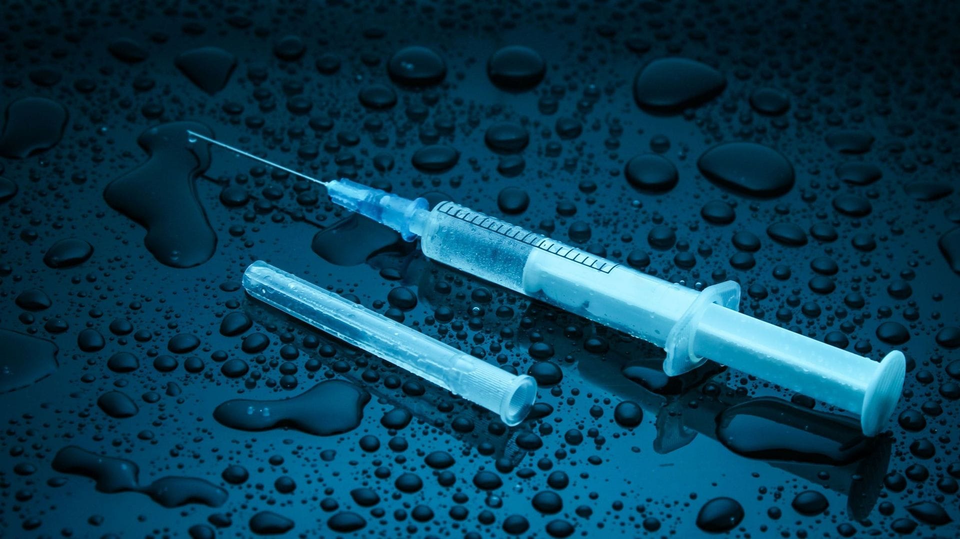 Seringue et ampoule sur surface mouillée, concept médical.