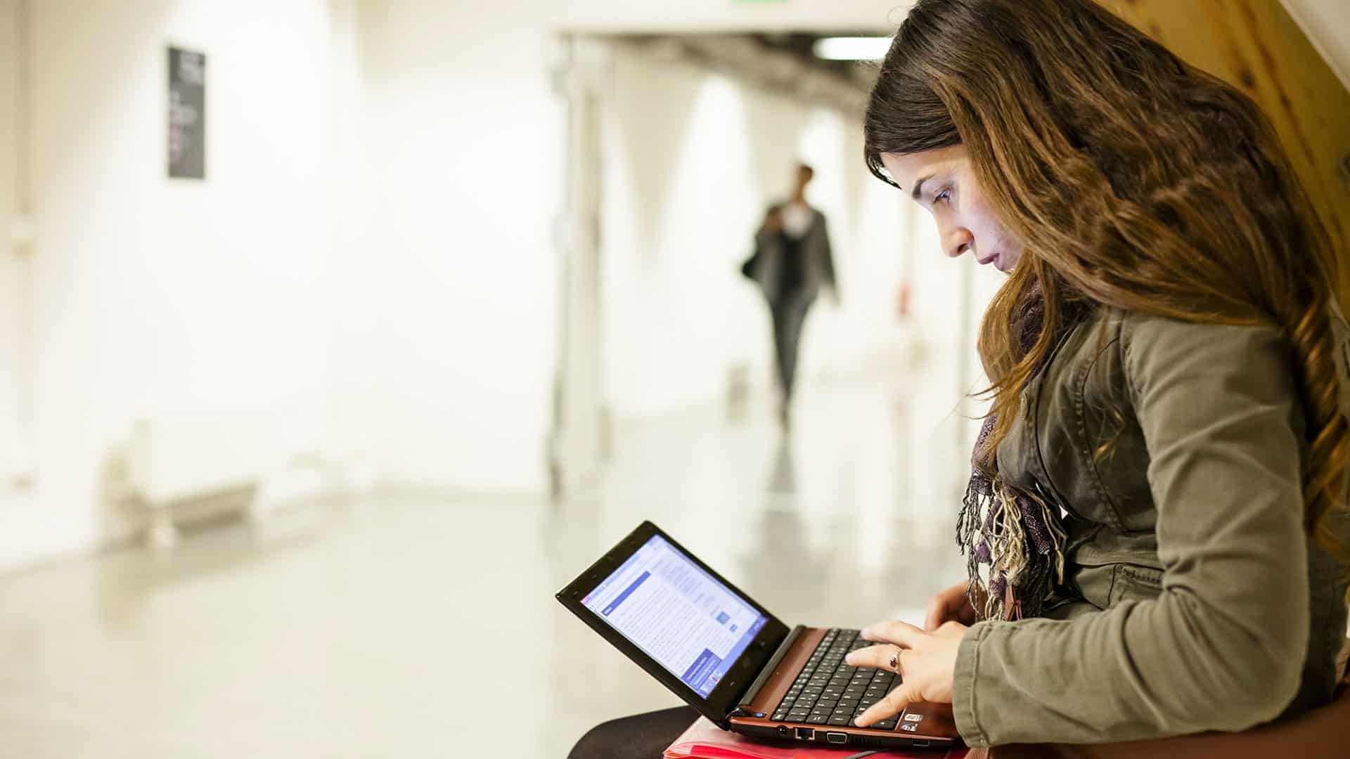 Jeune femme utilisant un ordinateur portable dans un espace public.