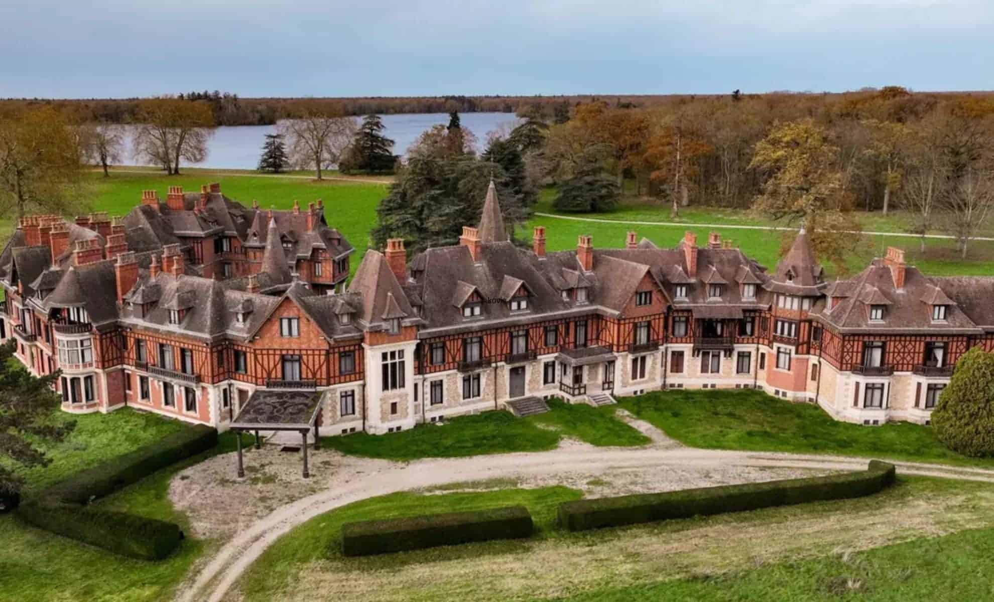 Magnifique château français avec jardins et lac en arrière-plan.