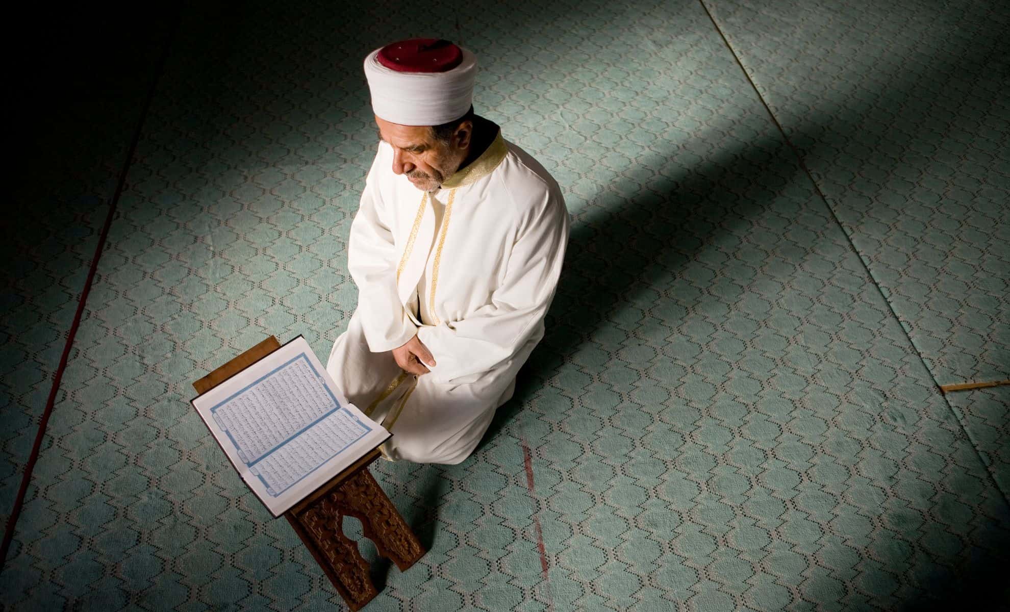 Imam en prière avec le Coran pendant Ramadan en Algérie.