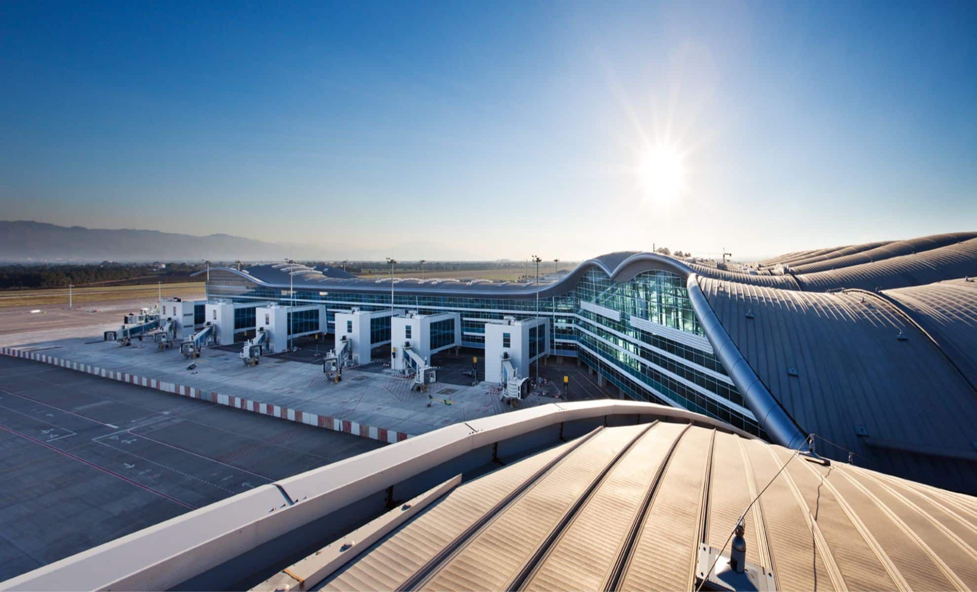 Vue aérienne de l'aéroport d'Alger avec terminal moderne et pistes.