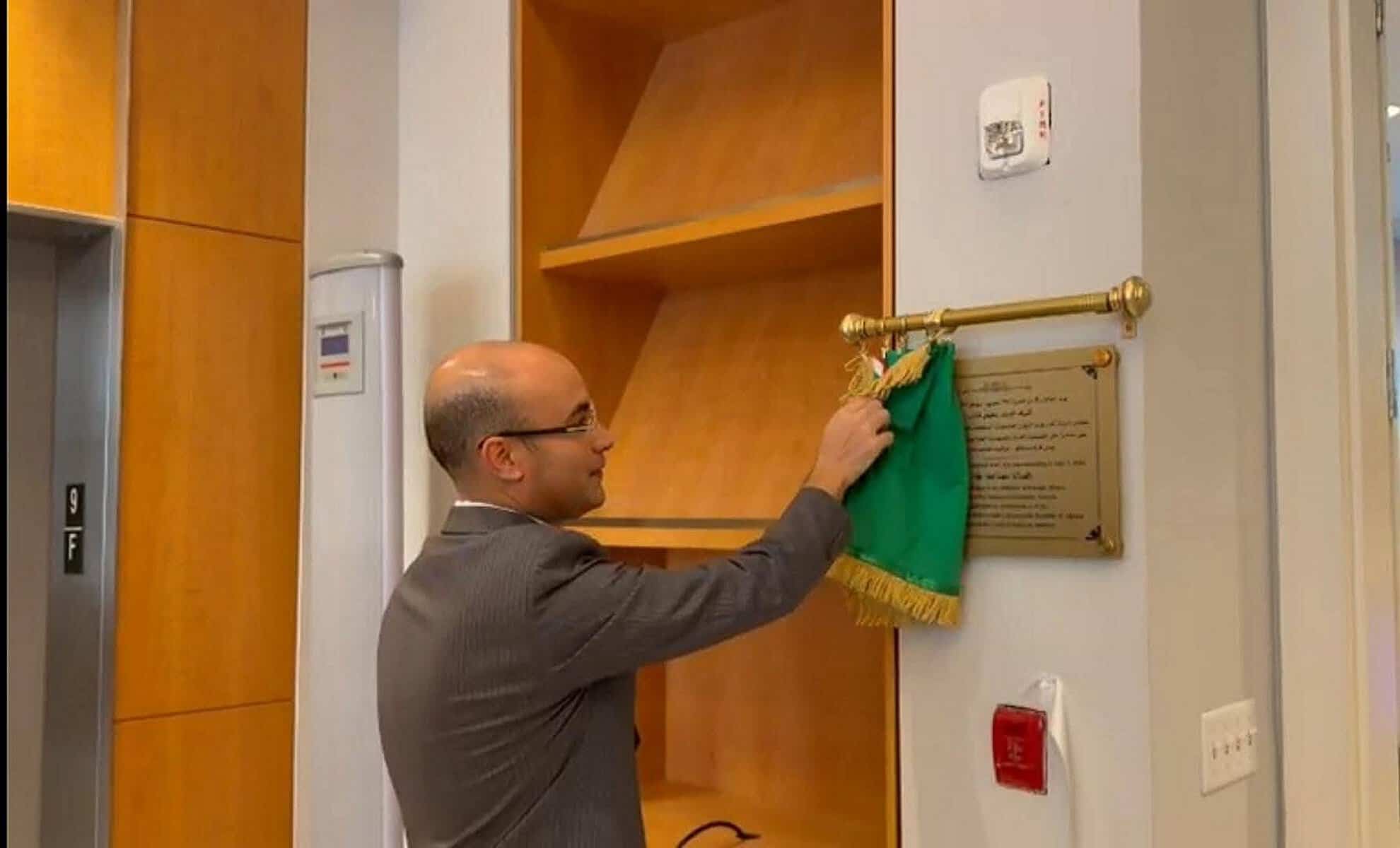 Homme dévoilant la plaque du nouveau consulat algérien aux USA.