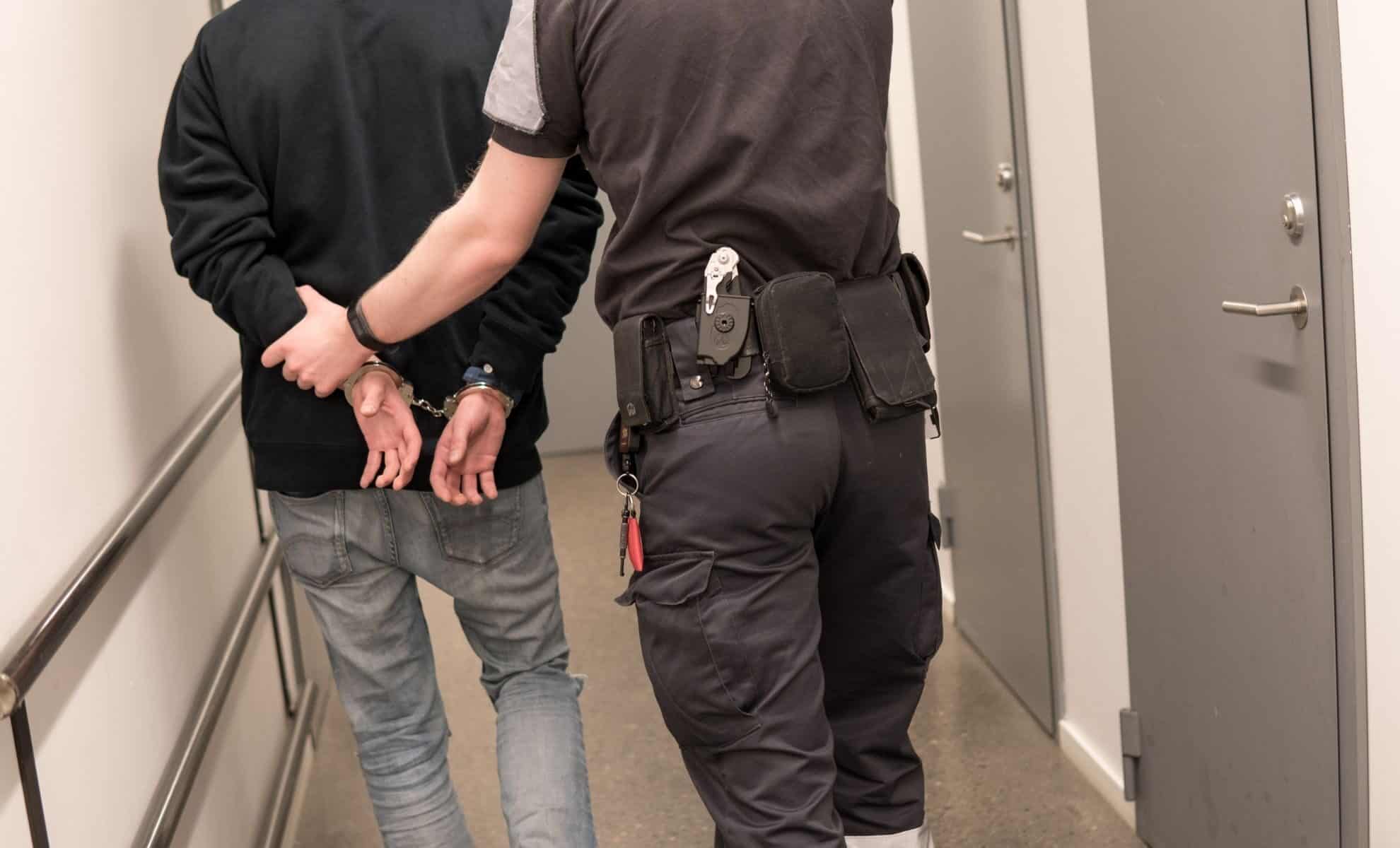 Agent de police arrêtant un homme dans un couloir.