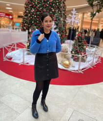 Mouni Bouallam posant devant un sapin de Noël décoré.