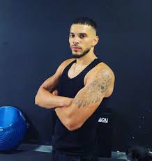 Homme musclé en tenue de sport dans une salle de gym moderne.