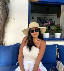 Yasmine Belkacem portant un chapeau et des lunettes de soleil à la plage.