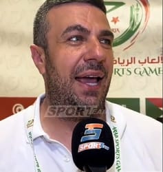Homme parlant à la presse lors d'un événement sportif en Algérie.