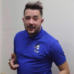 Homme souriant en polo bleu avec logo Mickey Mouse.