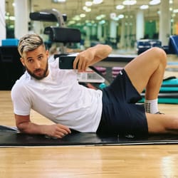 Homme prenant un selfie en faisant du sport dans une salle de gym moderne.
