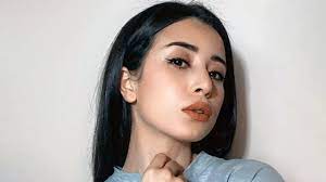 Jeune femme avec maquillage léger et cheveux noirs longs.