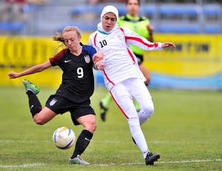 Deux footballeuses en action, l'une portant un hijab, lors d'un match féminin.