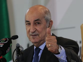 Homme politique donnant un signe de thumbs-up lors d'une conférence.