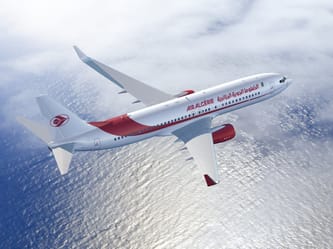 Avion Air Algérie survolant l'océan avec ciel nuageux.