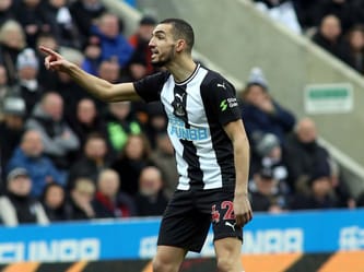 Footballeur algérien célèbre lors d'un match, pointant du doigt.