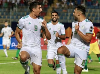 Joueurs de football algériens célébrant un but lors d'un match.