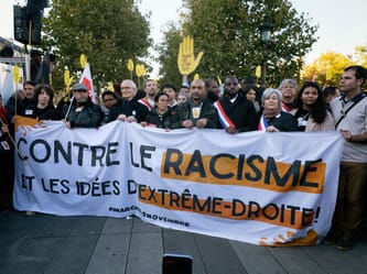 Groupe de manifestants tenant une bannière contre le racisme et l'extrême droite.