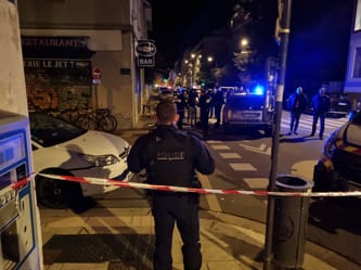 Policiers et véhicules de police sur une rue d'Aïn M'lila la nuit.