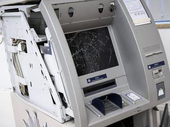 Distributeur de billets endommagé avec écran cassé.