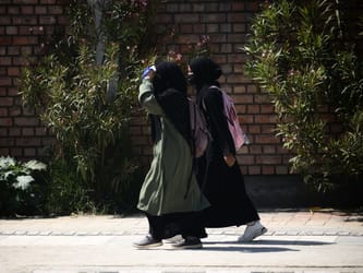 Deux femmes portant des abayas dans une rue urbaine.