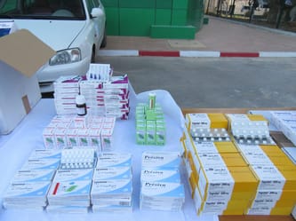 Médicaments et boîtes de médicaments disposés sur une table en extérieur.