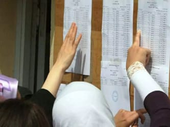 Étudiants vérifiant leurs résultats du BEM affichés sur un tableau.