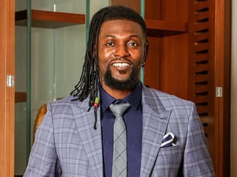 Emmanuel Adebayor en costume lors d'une conférence sur le football mondial.