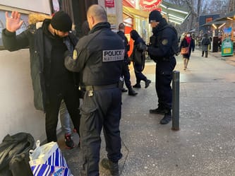 Policiers français contrôlant un homme dans une rue animée.