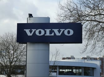 Panneau Volvo visible devant un bâtiment industriel en extérieur.