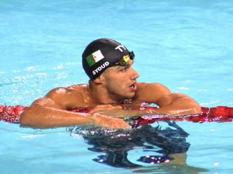 Nageur algérien portant un bonnet avec drapeau algérien et lunettes de natation.