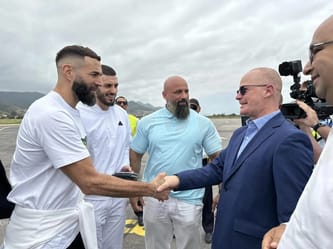 Karim Benzema serre la main d'un homme en costume lors d'une visite en Algérie.