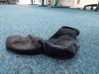 Chaussette abandonnée sur un tapis bleu dans un espace intérieur.