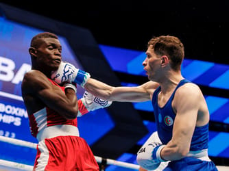 Deux boxeurs en combat lors des Jeux sportifs arabes, un en rouge et l'autre en bleu.