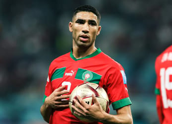 Achraf Hakimi en maillot du Maroc tenant un ballon de football.