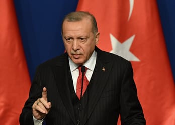 Recep Tayyip Erdoğan lors d'une conférence avec drapeaux turcs en arrière-plan.