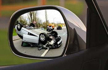 Voiture accidentée vue dans le rétroviseur d'un véhicule en déplacement.