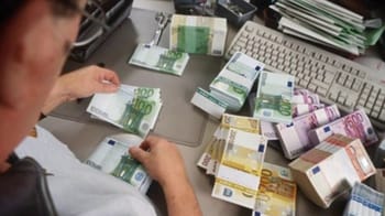 Personne comptant des billets en euros sur un bureau de bureau.
