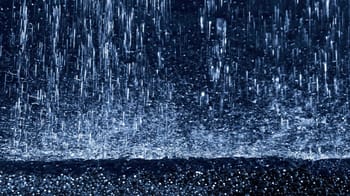 Gouttes de pluie tombant violemment sur une surface urbaine.