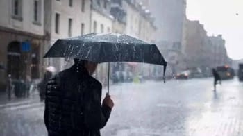 Personne avec parapluie noir sous la pluie dans une rue urbaine.