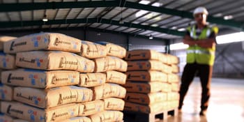 Ouvrier vérifiant le stockage de sacs de ciment dans un entrepôt.