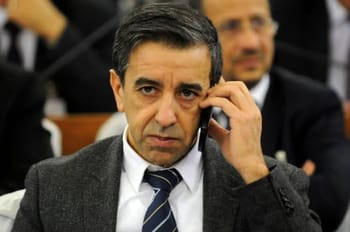 Ali Haddad au tribunal, en costume sombre, parlant au téléphone.
