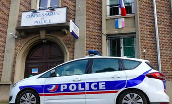 Voiture de police blanche avec logo POLICE devant un commissariat en France.