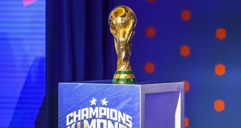 Trophée de la Coupe du Monde de football sur un podium bleu.